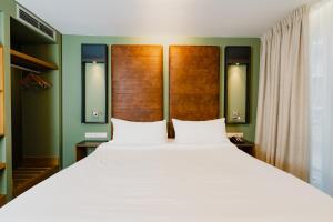 阿姆斯特丹哈伦酒店的卧室设有一张白色大床和绿色的墙壁