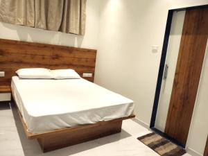 UlhāsnagarHotel Majestic的一间卧室配有一张带木制床头板的床