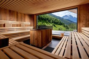 迈尔霍芬ZillergrundRock Luxury Mountain Resort的一间带木制长椅和大窗户的桑拿浴室