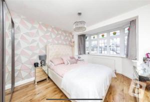 Harold WoodEnd of Terrace 4 bedroom 2 living room home in London的卧室配有白色床和粉红色枕头