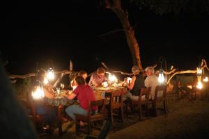 KwangwaziSelous River Camp的一群人晚上坐在桌子上