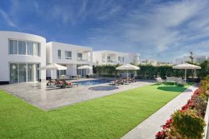 沙姆沙伊赫Rixos Golf Villas And Suites Sharm El Sheikh的一座带游泳池和庭院的大型白色房屋