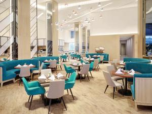 泗水泗水提木尔沙马托诺富特酒店的一间配备有蓝色椅子和桌子的用餐室