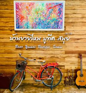 波普托Baan Yaimai Boutique Samui的一辆自行车停在木墙边,墙上挂着绘画