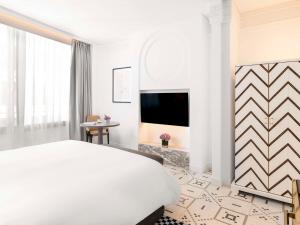 拉巴特Fairmont La Marina Rabat Sale Hotel And Residences的一间白色卧室,配有床和电视