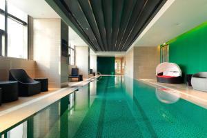 大连大连雅乐轩酒店的一座拥有绿色墙壁的建筑中的游泳池
