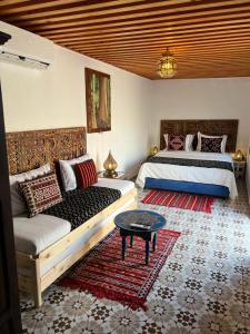 拉巴特Dar Mounia的一间卧室配有两张床、一张沙发和一张桌子