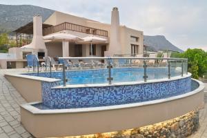 赫索尼索斯Ida villa的一座环绕着房子的蓝色瓷砖游泳池