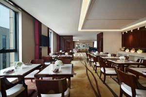 郑州郑州美盛喜来登酒店的餐厅设有木桌、椅子和大窗户。