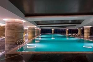 长春长春净月潭益田喜来登酒店的大楼内一个蓝色的大型游泳池