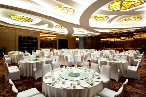 青岛青岛宝龙福朋喜来登酒店的一个带白色桌椅的大型宴会厅