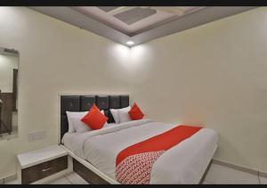 艾哈迈达巴德HOTEL SUNWAY的一间卧室配有一张带红色枕头的大床