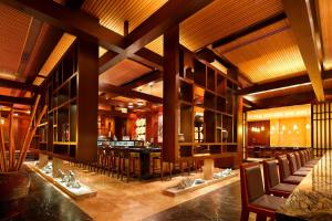 江阴江阴黄嘉喜来登酒店的一间带木制天花板和椅子的餐厅和一间酒吧