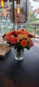 克诺克－海斯特Cosy Cottage Knokke的花瓶里满是橙色和红色的花朵