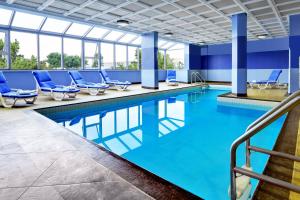米西索加福朋喜来登多伦多密西沙加酒店的大楼内带蓝色椅子的游泳池