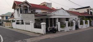 武吉丁宜Penginapan Terdekat (Near)的街上有一辆白色的房屋,上面有一辆摩托车