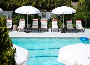 圣达菲艾尔瑞库尔特酒店的一组椅子和遮阳伞,位于游泳池旁