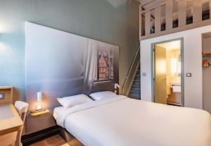 圣马丁德斯查B&B HOTEL Morlaix的卧室设有一张白色大床和楼梯。