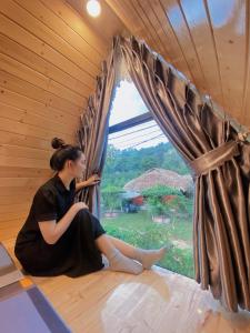 河内Xuhao Homestay的坐在窗外的房间里的一个女人