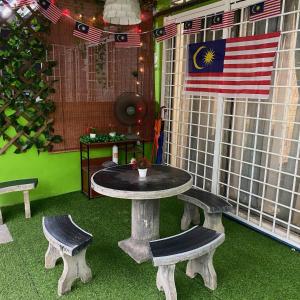 万挠Tulip Hijau Homestay - Bukit Beruntung - 4Bedrooms的天井配有桌子、长凳和美洲国旗。