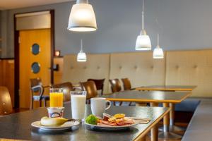 莱普海姆Hotel Leipheim Süd的餐桌,带食物盘和橙汁杯