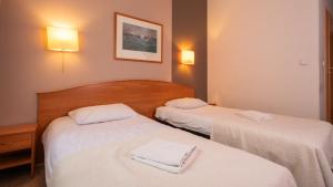 华沙佳雅酒店的两张位于酒店客房的床,配有毛巾