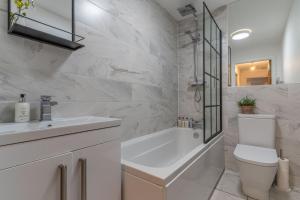 切斯特Luxury Chapel Apartment within City Walls的白色的浴室设有浴缸、卫生间和水槽。