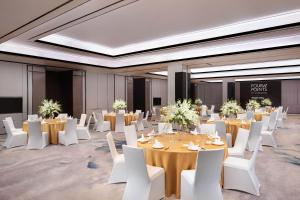 上海上海嘉定福朋喜來登酒店的一个带桌子和白色椅子的宴会厅以及一间配有桌子和白色的