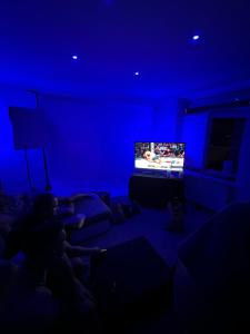 纳霍德FLY5 Gaming Spot的躺在蓝色房间沙发上看电视的人