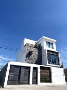 特克塞丁戈Hermosa casa familiar de fin de semana en Teques的一座高大的白色建筑,设有窗户和门