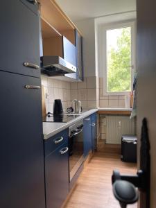 伊瑟隆Wohnen am Wanderbahnhof Iserlohn的一间设有蓝色橱柜和窗户的小厨房