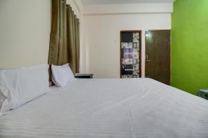 KorādihSuper OYO Hotel Elite Inn的一张白色的大床,位于一个绿色的墙壁上