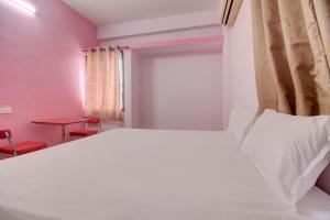 KorādihSuper OYO Hotel Elite Inn的卧室配有白色的床和红色的桌子