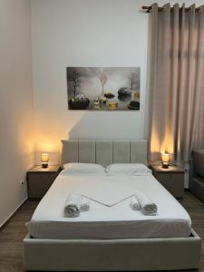 地拉那Gex apartments的卧室配有一张带两盏灯的白色床和一幅画