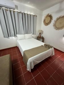 马萨特兰Creta Hotel & Suites的卧室配有白色的床和红色瓷砖地板。