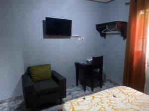 杜阿拉Sunrise Center Bonapriso 104的一间卧室配有一张床、一把椅子和电视。