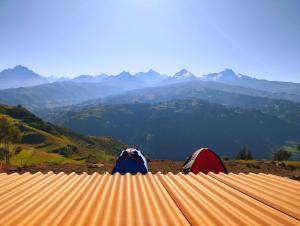 瓦拉斯mountain view willcacocha lodge的两人坐在屋顶上,眺望着群山