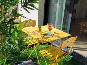 阿尔蒂盖普雷博尔多Paisible, spacieux avec petit jardin的黄色的桌子和椅子,上面有饮料