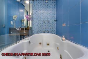阿雷格里港Motel Porto dos Casais的浴室铺有蓝色瓷砖,配有白色浴缸。
