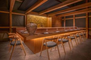 奈良Shisui, a Luxury Collection Hotel, Nara的餐厅设有长长的酒吧,配有椅子和花瓶