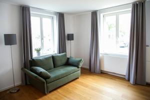 梅尔布施Green46的客厅设有绿色沙发和2扇窗户。