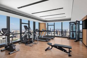 昆明昆明新迎万枫酒店的一个带跑步机和有氧运动器材的健身房,位于带窗户的房间内