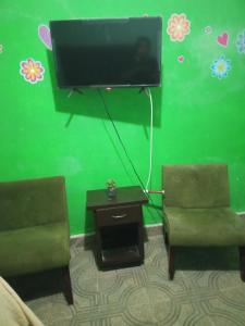 蒙特雷Recamara confortable en San Nicolás的客厅配有2把椅子和平面电视