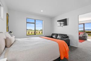 陶波Wai Escape - Taupo Holiday Unit的一间卧室配有一张床、一把椅子和窗户。