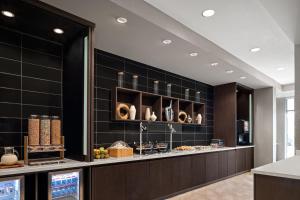 波蒂奇SpringHill Suites by Marriott Kalamazoo Portage的厨房铺有黑色瓷砖,配有带食物的柜台。