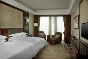 沈阳沈阳新都绿城喜来登酒店的酒店客房设有两张床和一台平面电视。