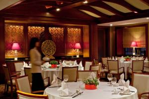 上海上海齐鲁万怡大酒店的一间设有白色桌椅的餐厅,以及一间女士餐厅
