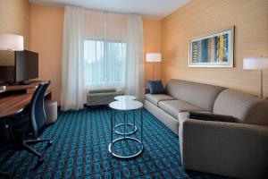 东叙拉古万豪锡拉丘兹卡里尔环岛费尔菲尔德客栈的一间客厅,客厅配有沙发和一张书桌,位于酒店的房间