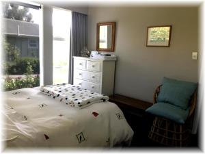 Pukerua BayPeaceful Pukerua Bay的卧室配有床、椅子和窗户。