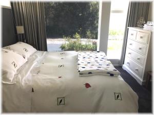 Pukerua BayPeaceful Pukerua Bay的一间卧室配有一张带白色床单的床和一扇窗户。
